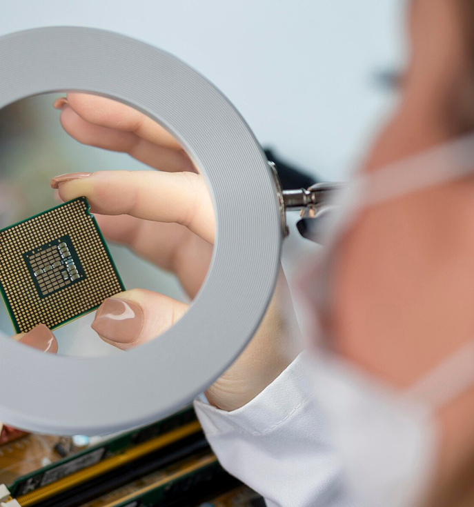 Technician inspecting a microprocessor under a magnifying lamp