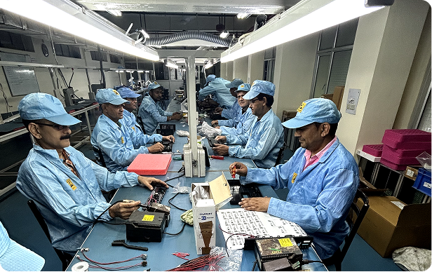 Assembly line workers in cleanroom gear inspecting electronic boards